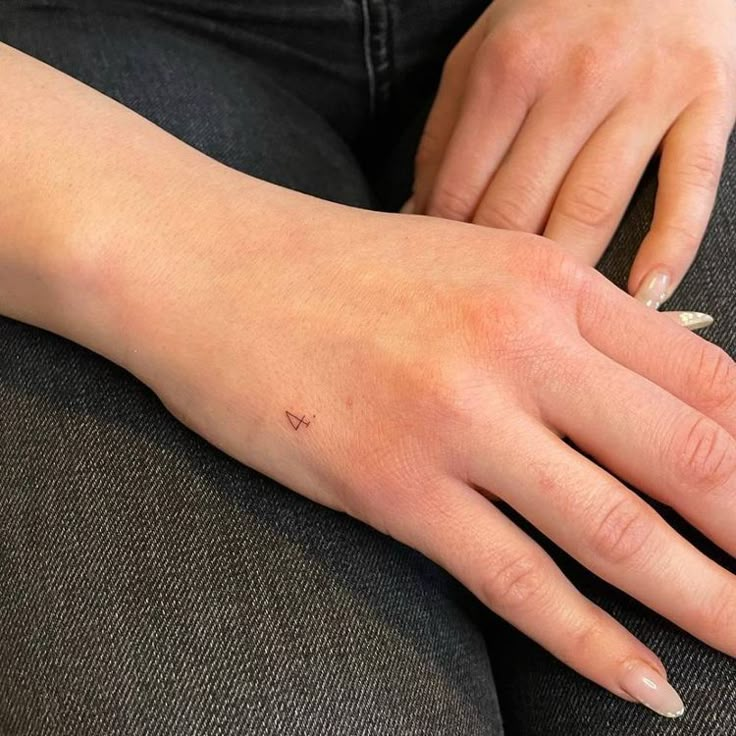 a woman's hand with a tiny heart tattoo on it