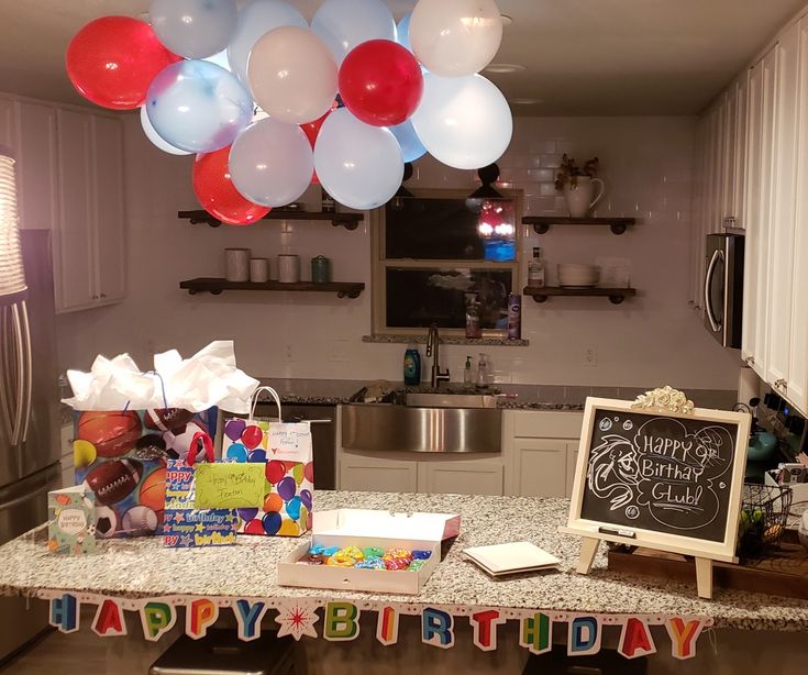 a birthday party with balloons and gifts on the counter