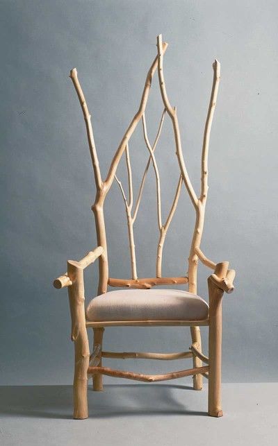 a black and white photo of a chair with branches on it's backrest