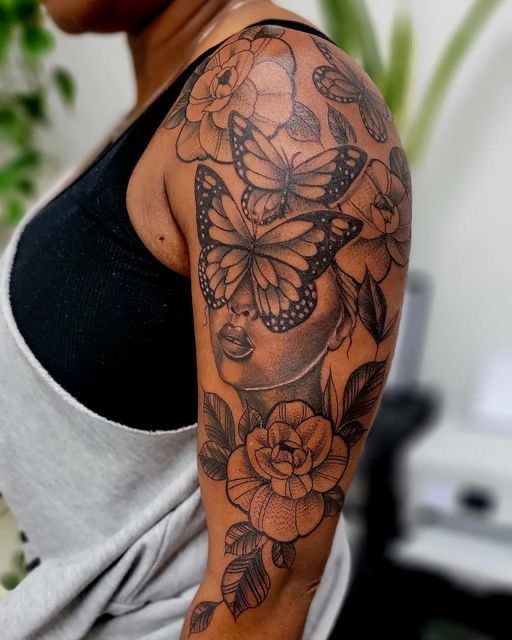 a woman with a butterfly tattoo on her arm and shoulder, holding onto a flower