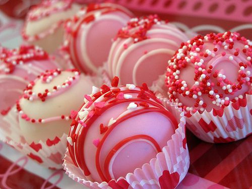 red and white candies with sprinkles are on a plate in the shape of hearts