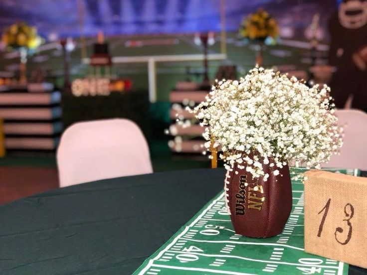 a football themed centerpiece with baby's breath flowers on the table at a sports event