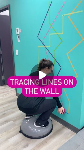 a woman kneeling on top of a floor next to a wall with lines painted on it