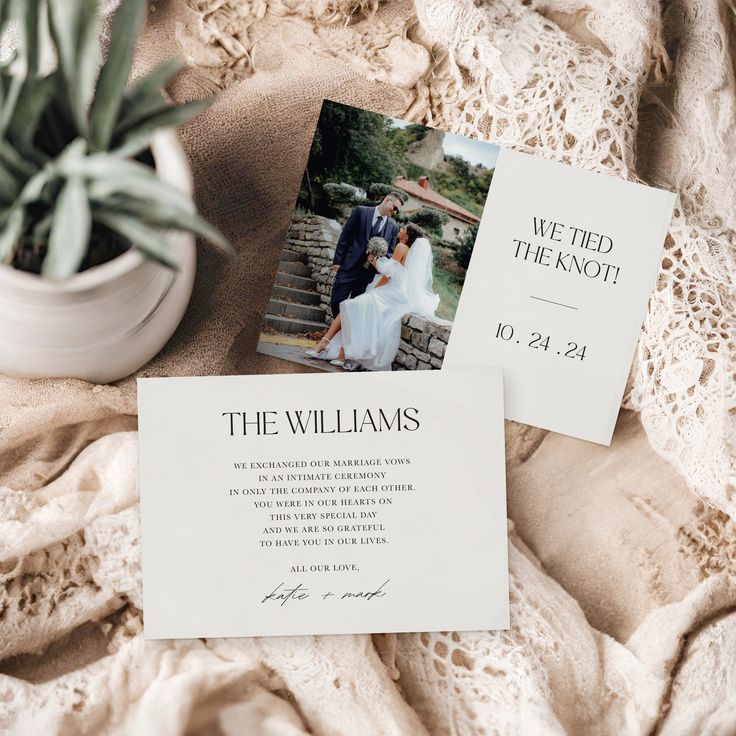 two wedding cards on top of a bed next to a potted plant and an envelope