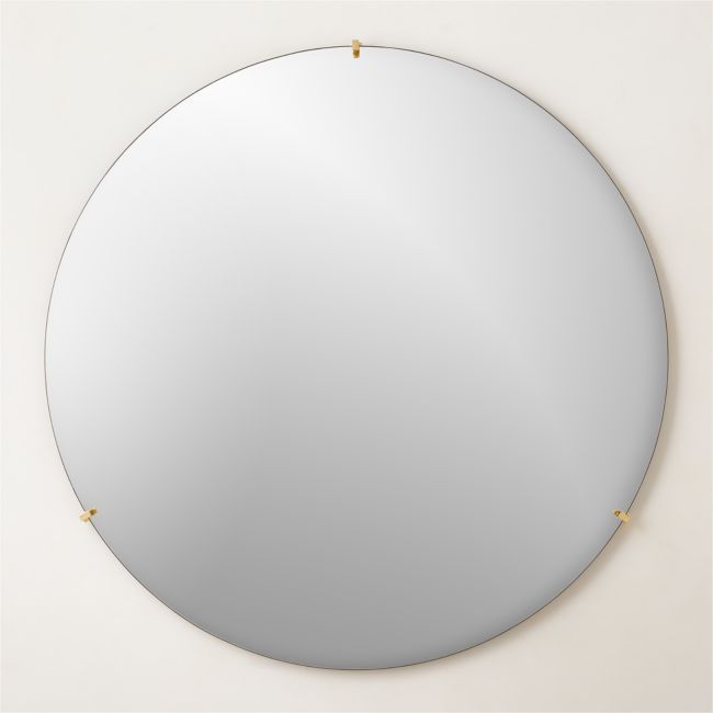 a round mirror with gold studs on the edges and a white wall behind it