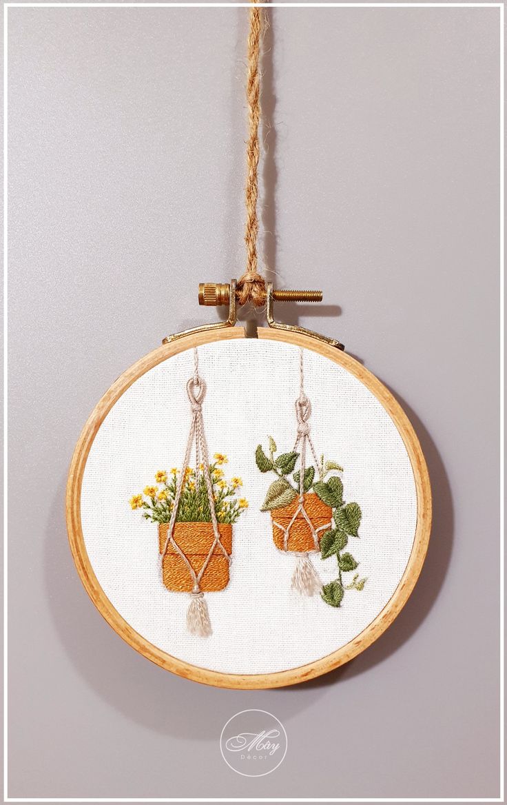 two potted plants are hanging from a rope on a white wall behind a wooden frame