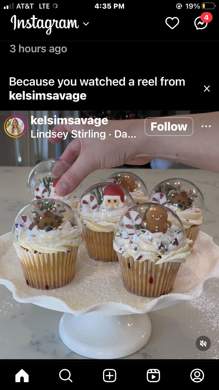 cupcakes are sitting on a plate with snow globes in the middle and someone holding them