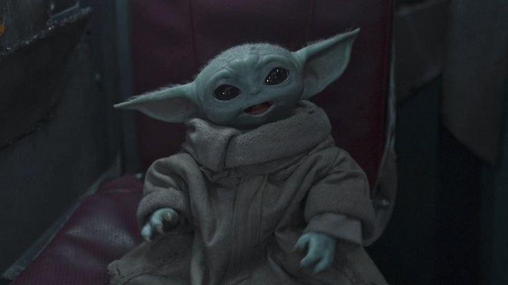 a baby yoda doll sitting on top of a red chair