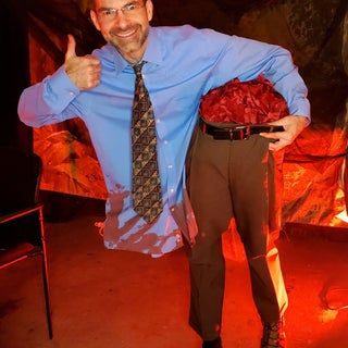 a man is standing in front of a fire holding a bouquet of flowers and giving the thumbs up sign