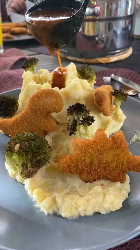 a plate topped with mashed potatoes and broccoli covered in sauce