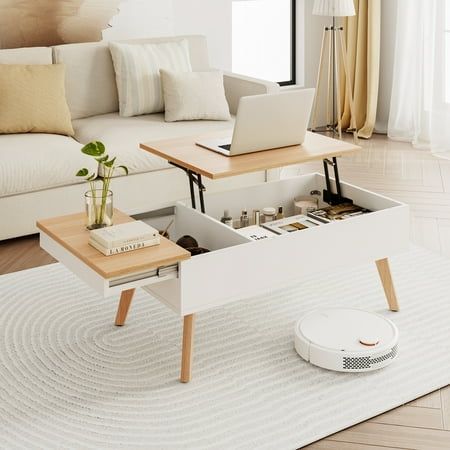 a living room with a couch, coffee table and laptop on top of it in front of a window