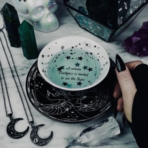 a person holding a spoon over a bowl on top of a table next to other items