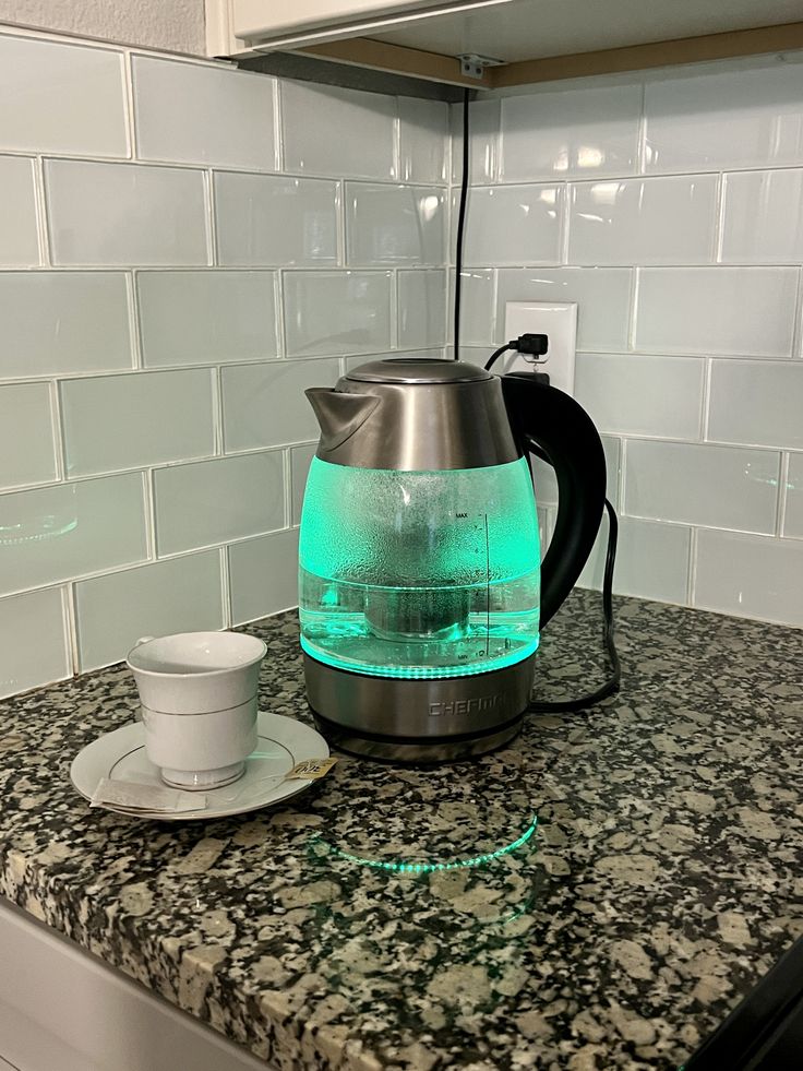 a tea kettle sitting on top of a counter next to a cup and saucer