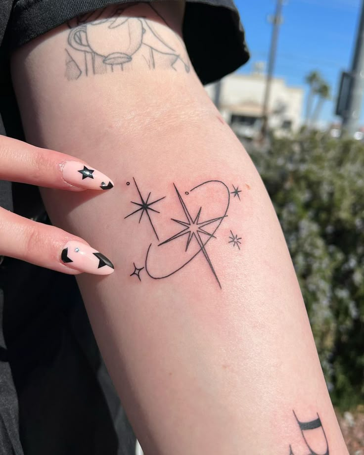 a woman's arm with tattoos on it and stars in the sky above her