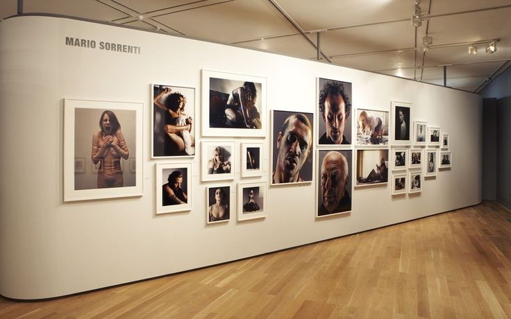 a wall with many pictures on it in an art gallery or museum, showing women's nude torsos