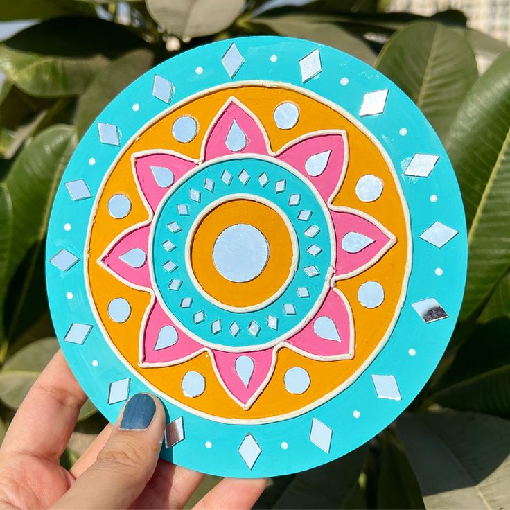 a hand holding up a paper plate with designs on it