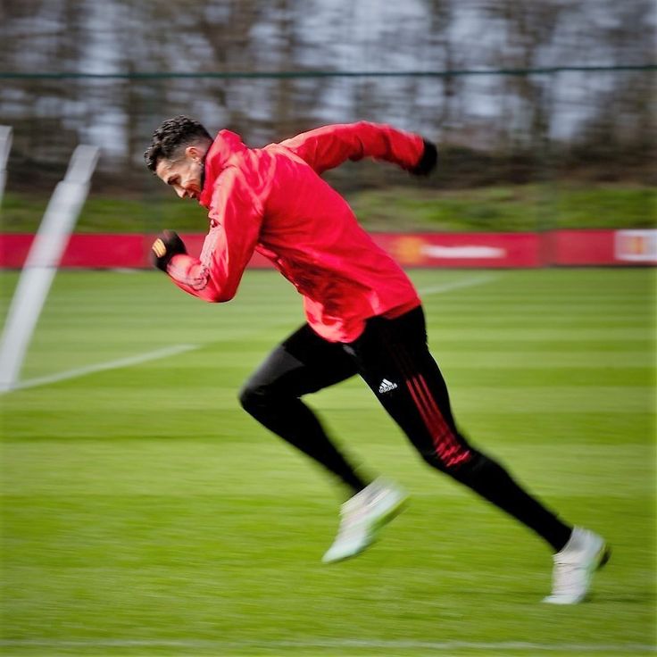 a man is running in the grass with a frisbee on his hand while wearing a red jacket and black pants