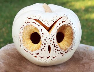 an owl carved into a pumpkin sitting on top of a foil covered table with other items