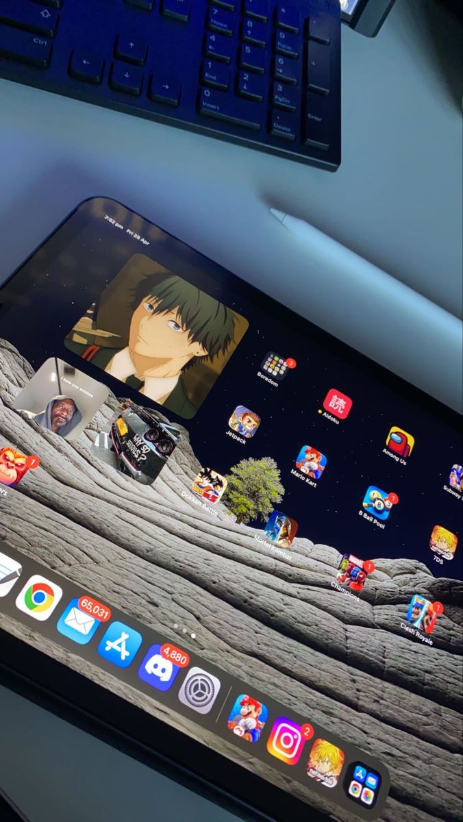 an ipad sitting on top of a desk next to a keyboard and monitor with anime icons