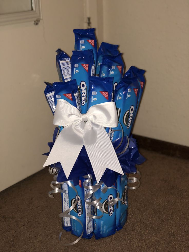 a basket filled with blue candy wrapped in white ribbon and tied to the side, sitting on top of a carpeted floor