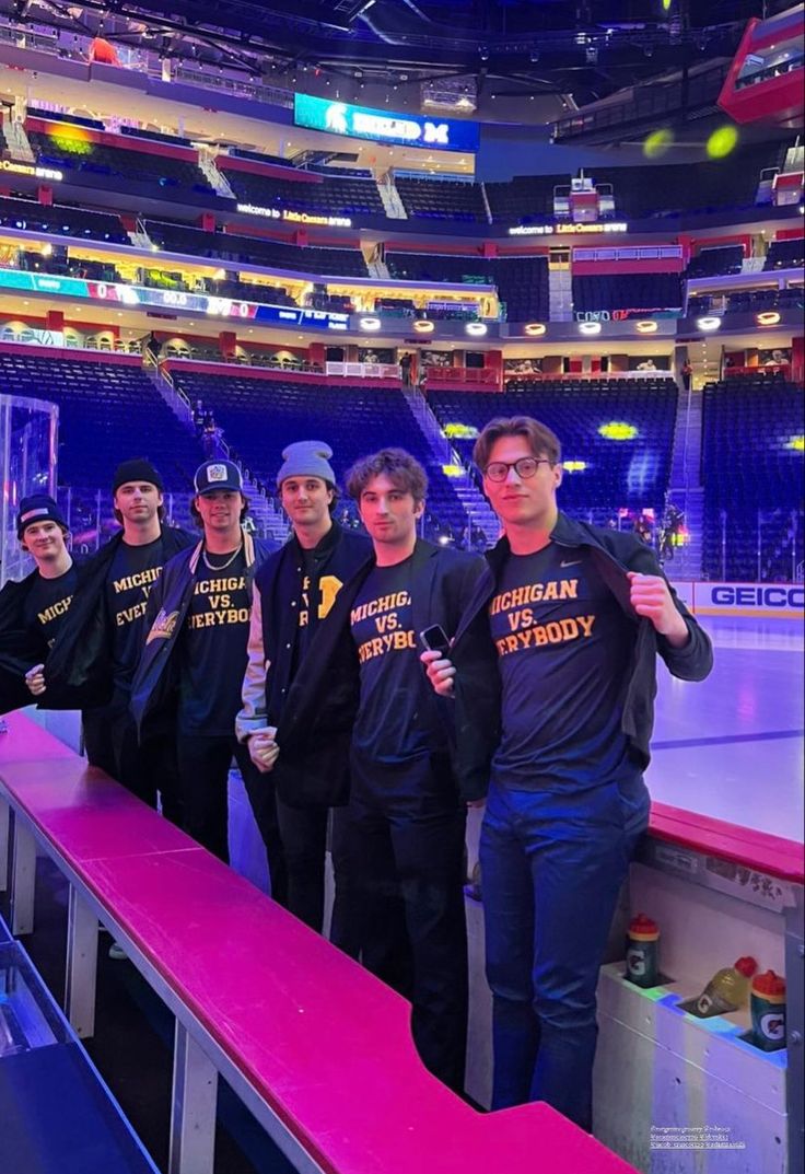 a group of men standing next to each other in front of an ice rink