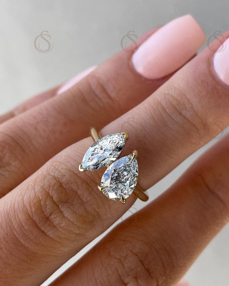 a woman's hand with two engagement rings on it and one ring is in the middle