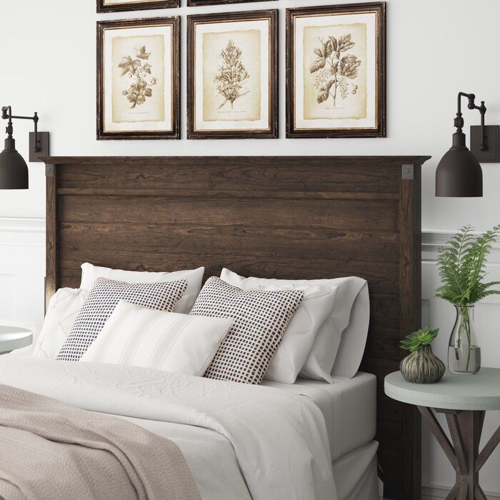 a bed with white sheets and pillows in a bedroom next to two pictures on the wall