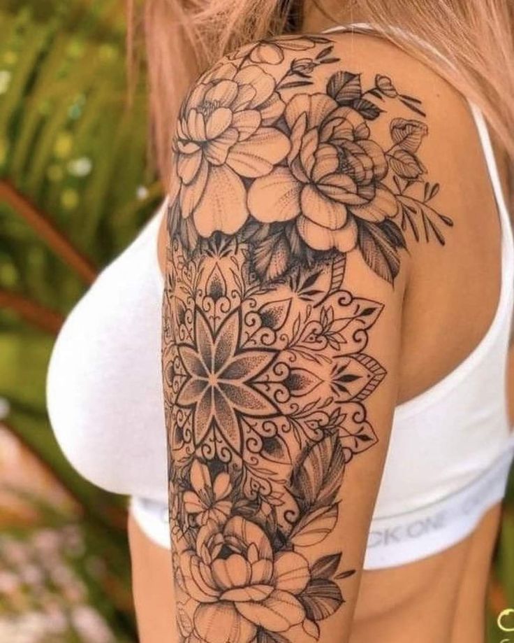 a woman's arm with flowers and leaves tattooed on the back of her shoulder