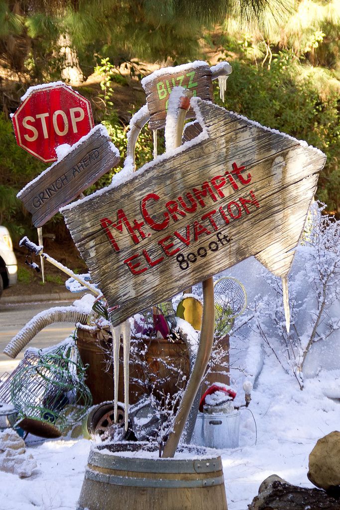 a wooden sign sitting on top of a barrel in the snow next to a stop sign