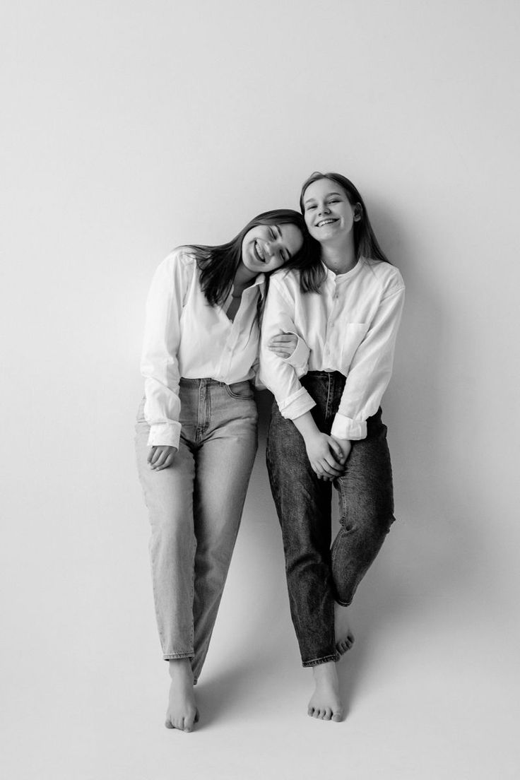 two young women are posing for a black and white photo in front of a wall