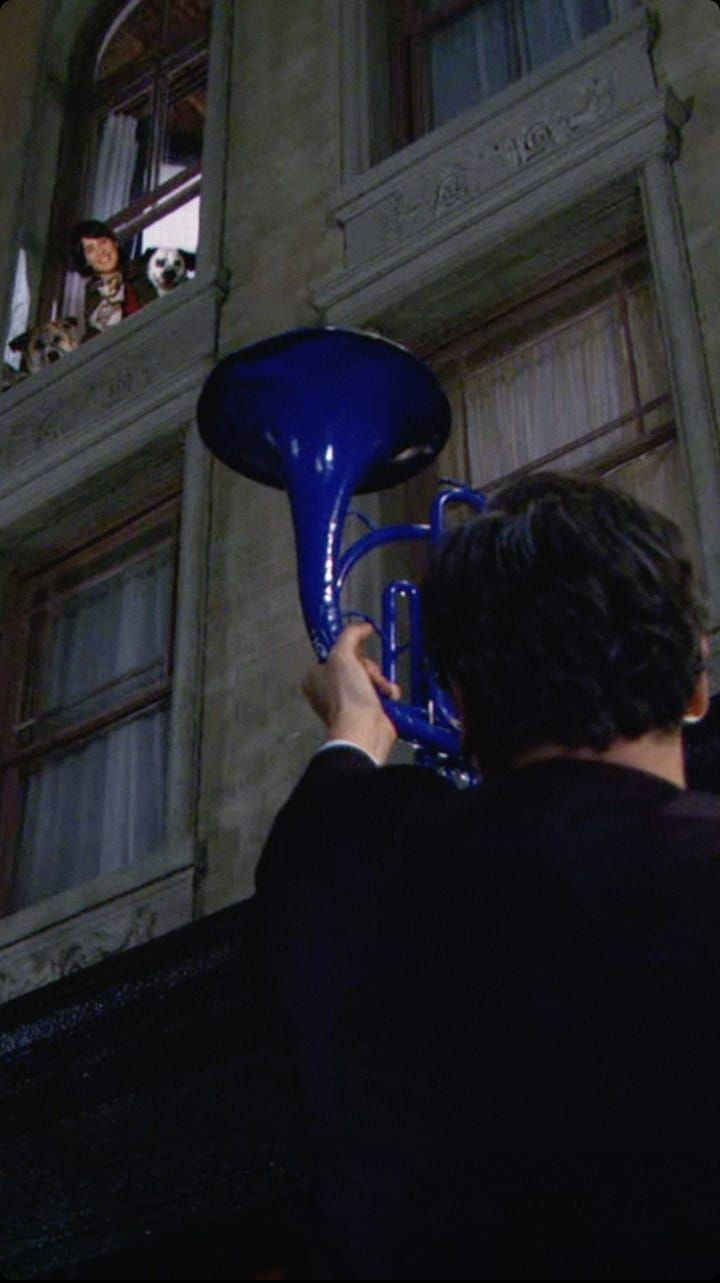 a man holding a blue trumpet in front of a building