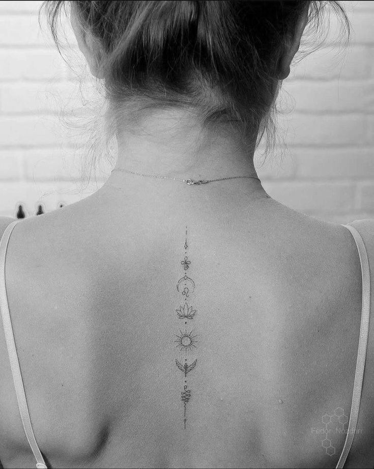 the back of a woman's neck with tattoos on her upper and lower back