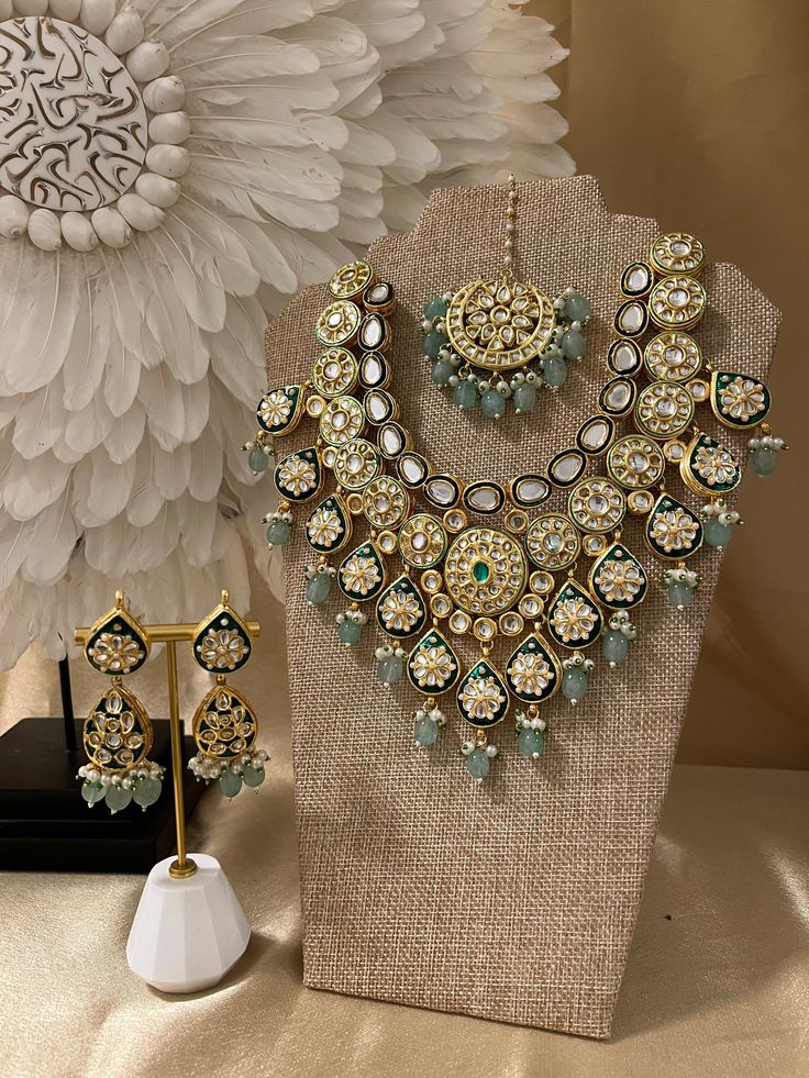 a necklace and earring set on display next to a white flower vase with flowers in the background