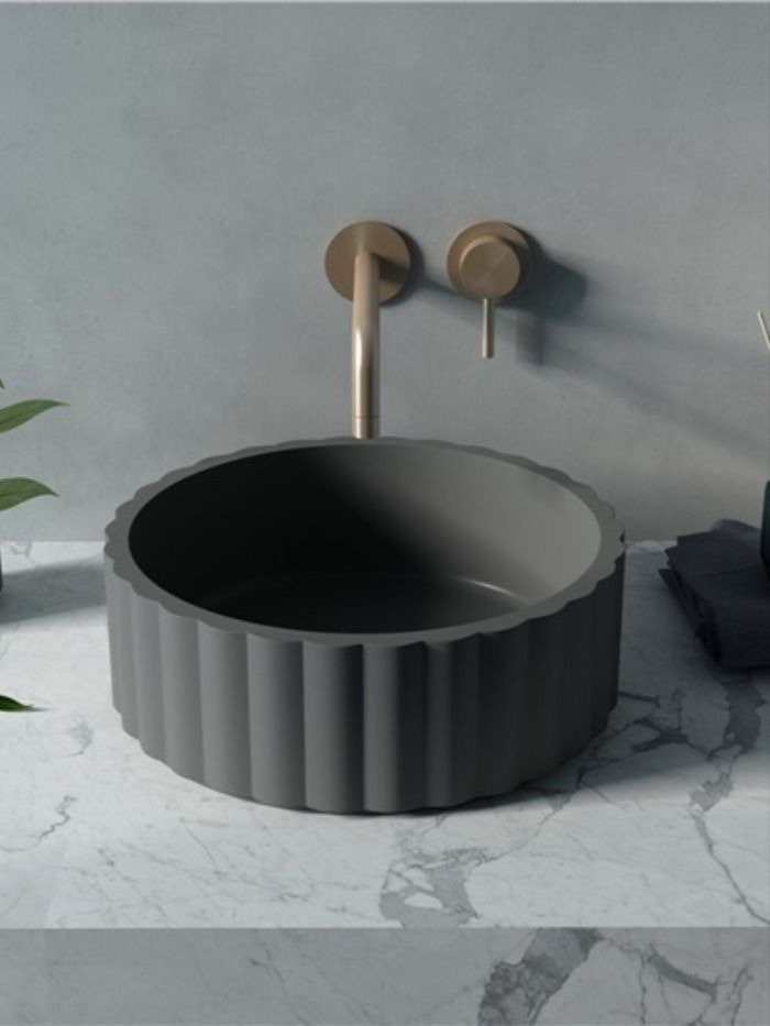 a round sink sitting on top of a white counter next to a potted plant