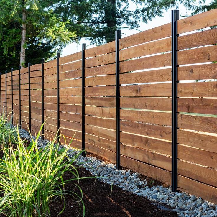 a wooden fence with metal posts and gravel