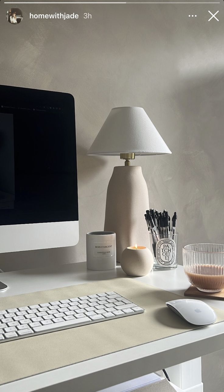 a desktop computer sitting on top of a desk next to a lamp and glass vase