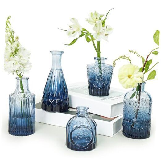 blue glass vases with flowers in them sitting on a white table top next to each other