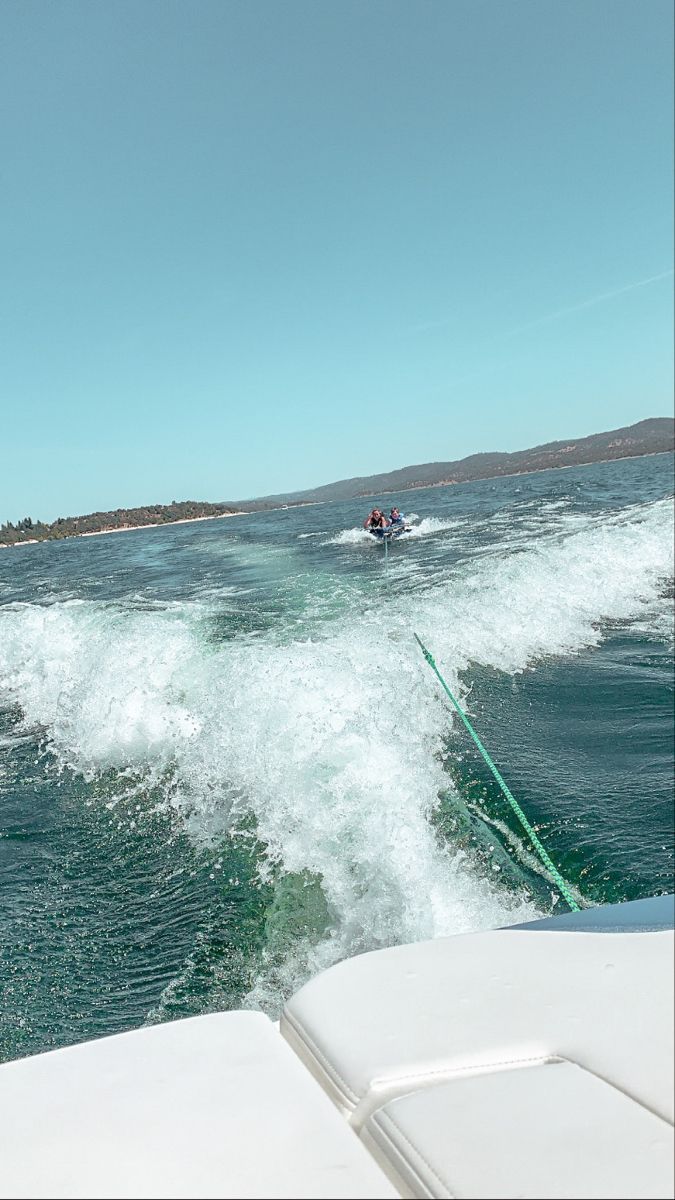 a person on a surfboard in the water near another boat with people riding it