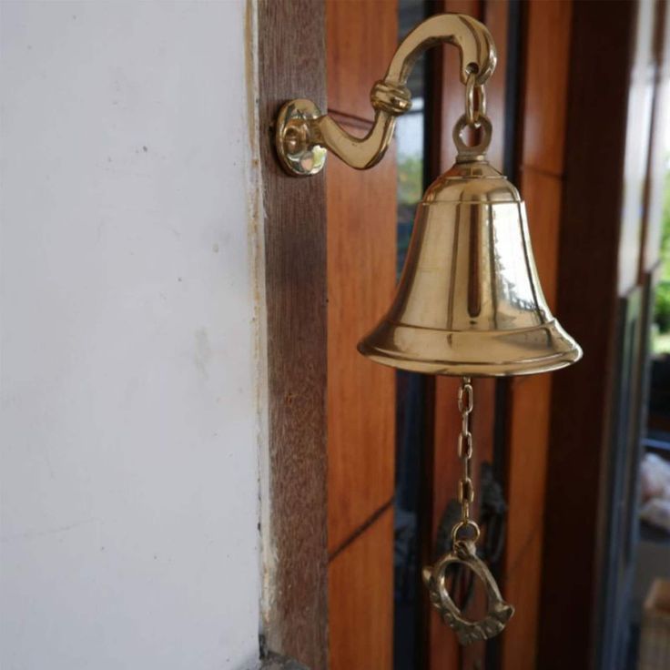 a golden bell hanging from the side of a door