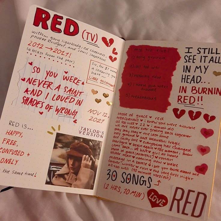 an open book with red writing and pictures on the pages is laying on a bed