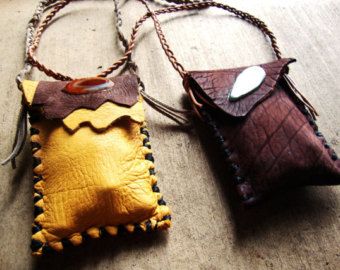 two leather purses sitting on top of a wooden floor next to each other, one has a button and the other has a chain