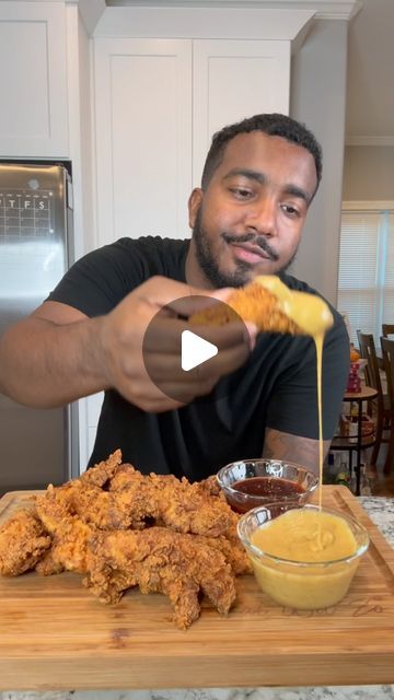 a man is pouring sauce on chicken wings and dipping them into a small bowl with mustard