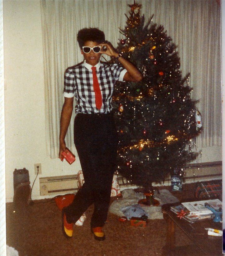 an old photo of a man standing in front of a christmas tree with sunglasses on