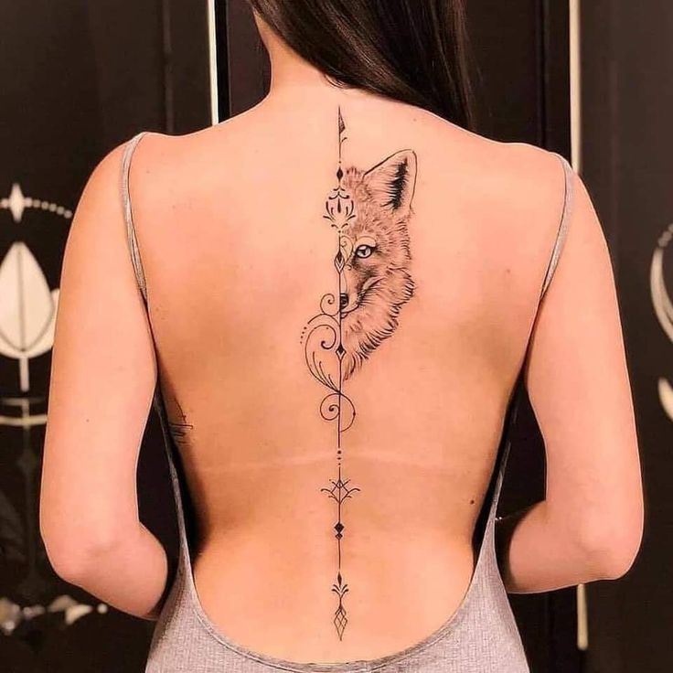 the back of a woman's neck with a fox and arrow tattoo on it