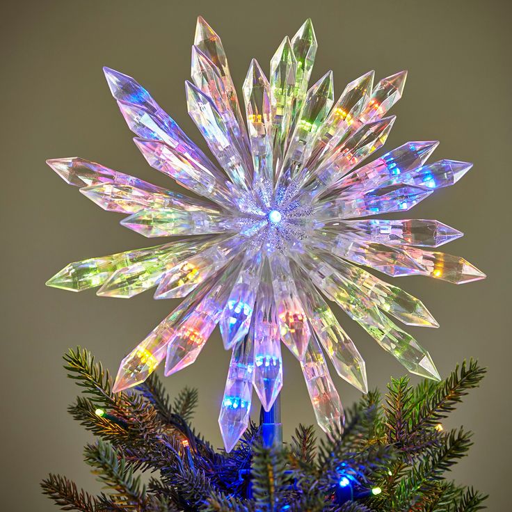 a christmas tree decorated with multicolored lights and snowflaked decorations on top