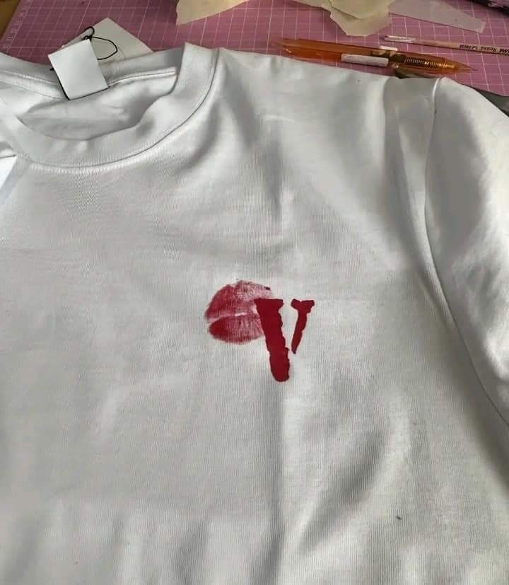 a white shirt with the letter v painted on it and a pencil next to it