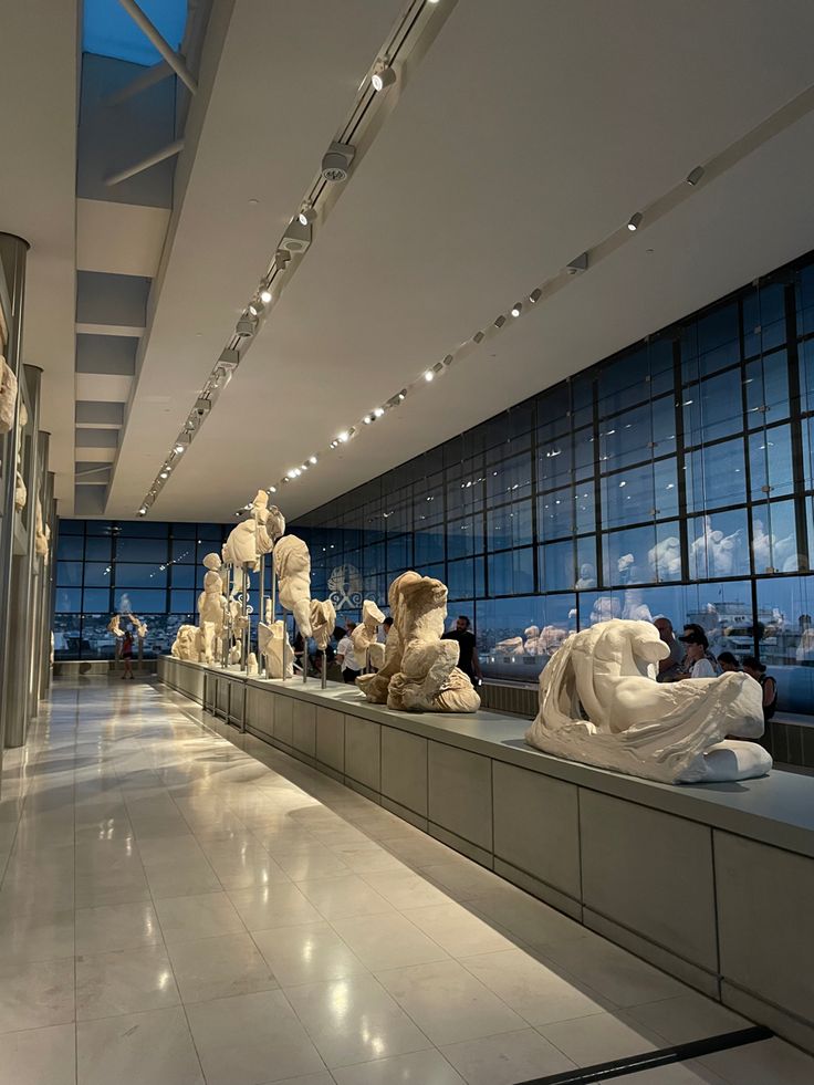 an art gallery with sculptures on display in front of glass walls and floor to ceiling windows