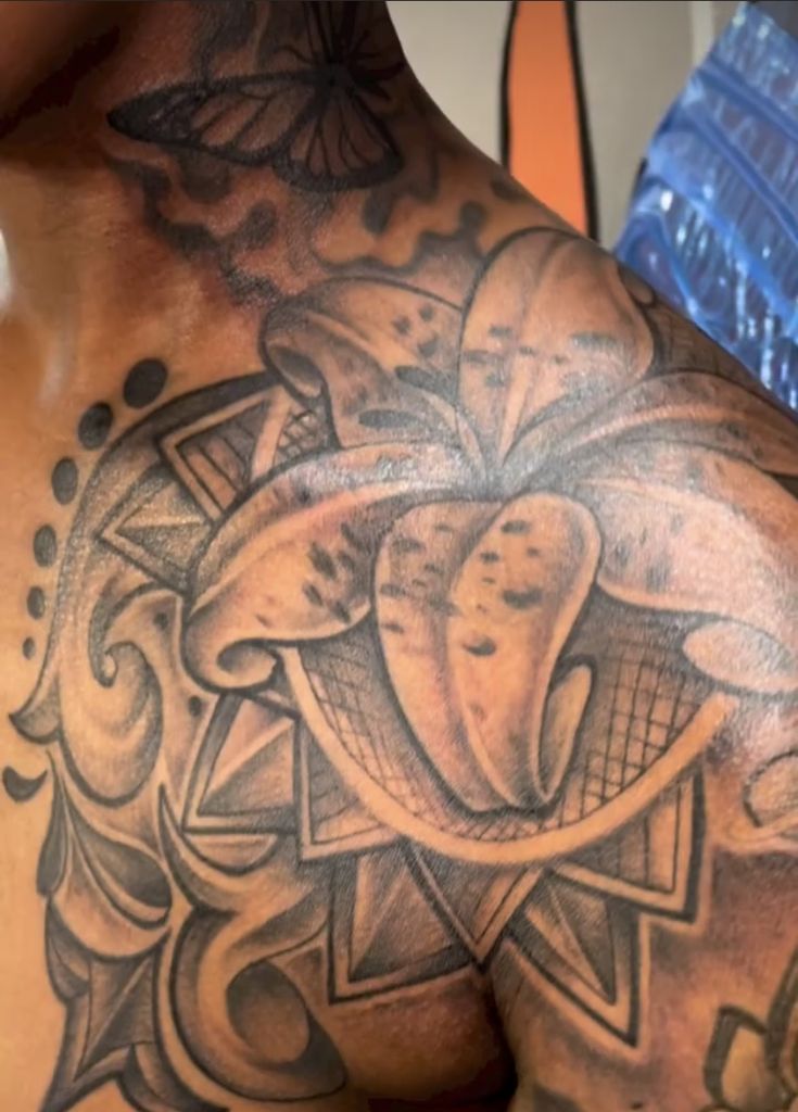 the back of a man's shoulder with an artistic tattoo design on his chest