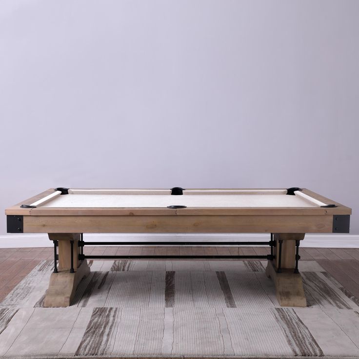 a pool table in the middle of a room with a rug on the floor next to it