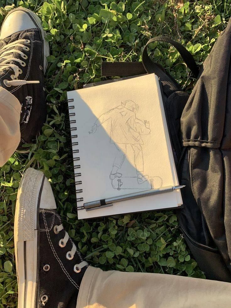 someone's feet and notebook on the ground next to their shoes with a drawing of a baseball player